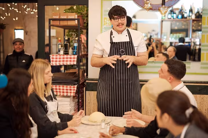 Chef instructing a group in a hands-on pizza cooking class near Piazza Navona in Rome city center.