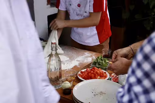 Hands prepare traditional Neapolitan pizza dough with fresh toppings during a small-group Naples pizza master class