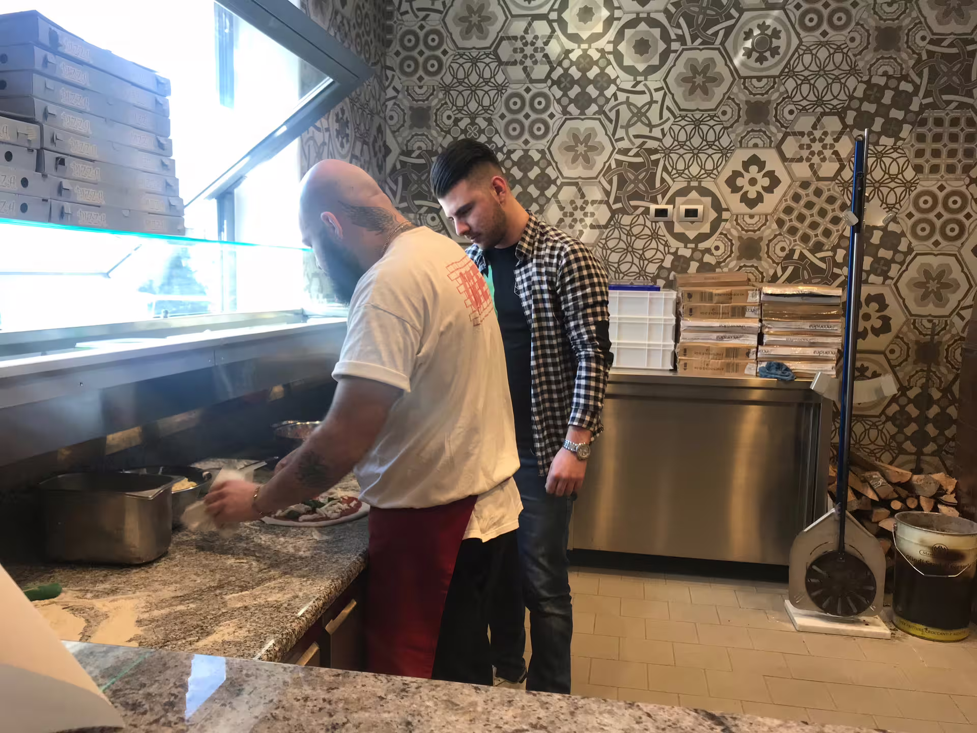 Guest learning dough shaping with a pizzaiolo in Naples pizzeria kitchen during hands-on Neapolitan pizza class