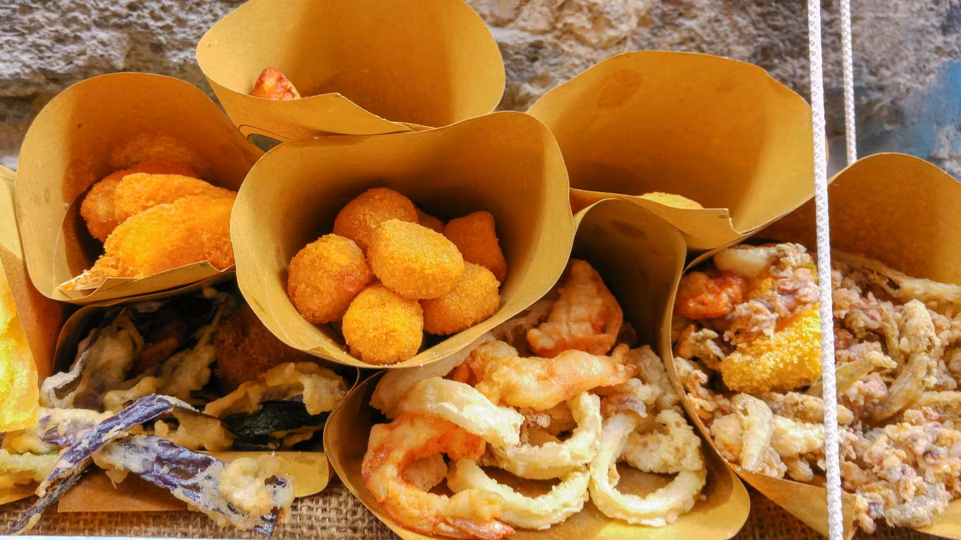 Assorted traditional Neapolitan street food like fried seafood and arancini in paper cones, perfect for tasting tour.