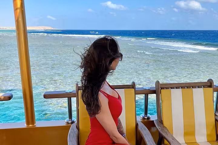 Guest relaxing on Nefertari cruise from Makadi, overlooking Red Sea reef before snorkeling, pickup included