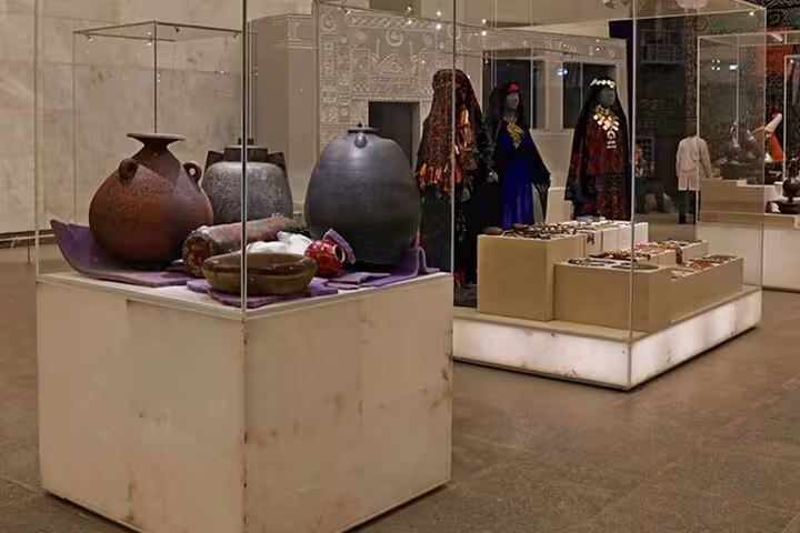 NEMC museum gallery with ancient Egyptian pottery, jewelry displays and traditional costumes on private Cairo tour