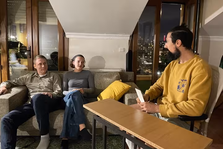 Networking Turkish tea tasting in Istanbul apartment lounge, guests chatting with host over tea and city views