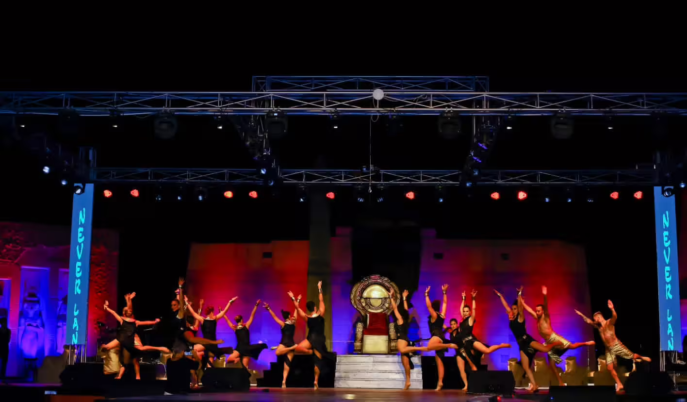 Neverland musical and cabaret show finale with ensemble dancers leaping across stage under colorful lights