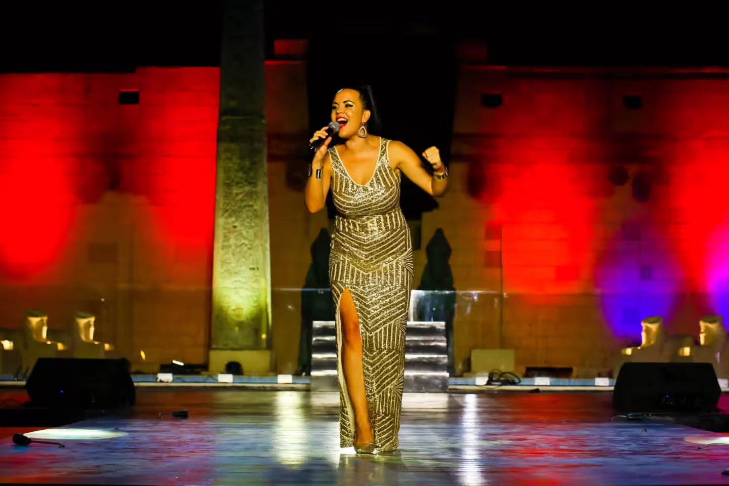 Lead singer in glitter gown performs live at Neverland Musical and Cabaret Show with dramatic stage lights