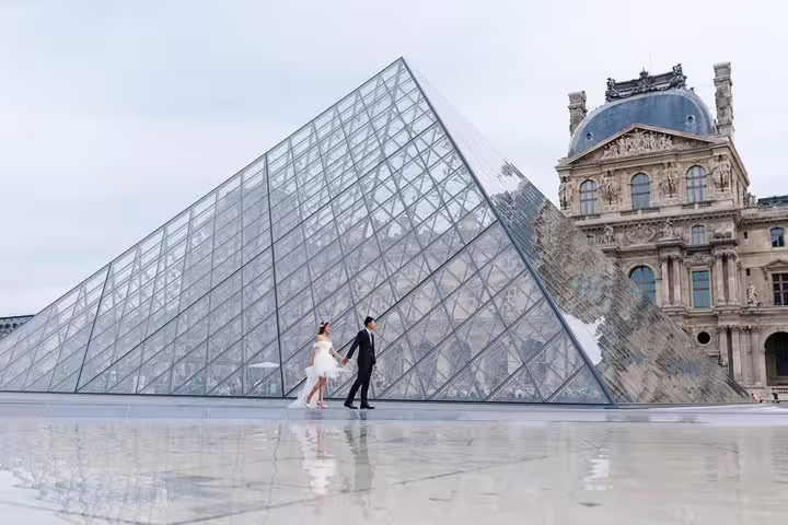 Newlyweds walking by the Louvre Pyramid in Paris on a private travel photographer tour, elegant photo session