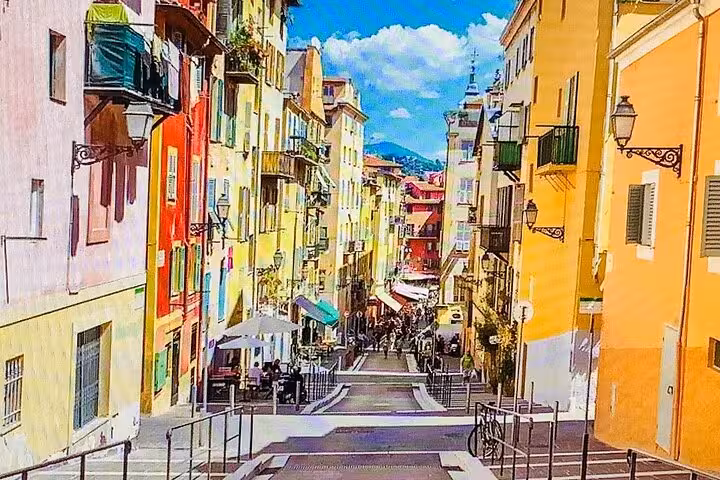 Colorful street in Nice, France, showcasing vibrant architecture under a bright blue sky, ideal for a cultural city tour.