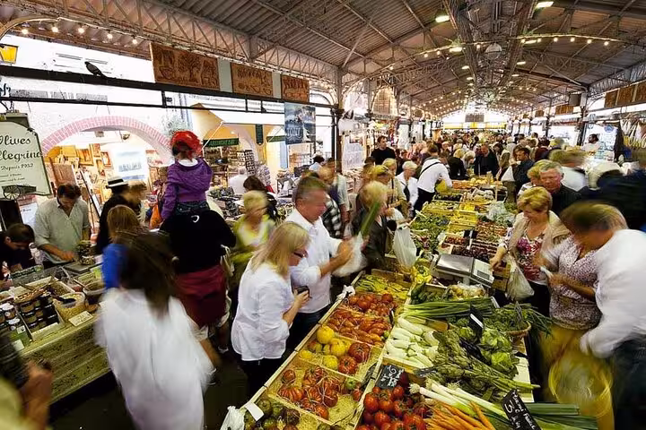 Vibrant indoor market in Nice bustling with people exploring fresh produce and local delicacies on a French Riviera tour.