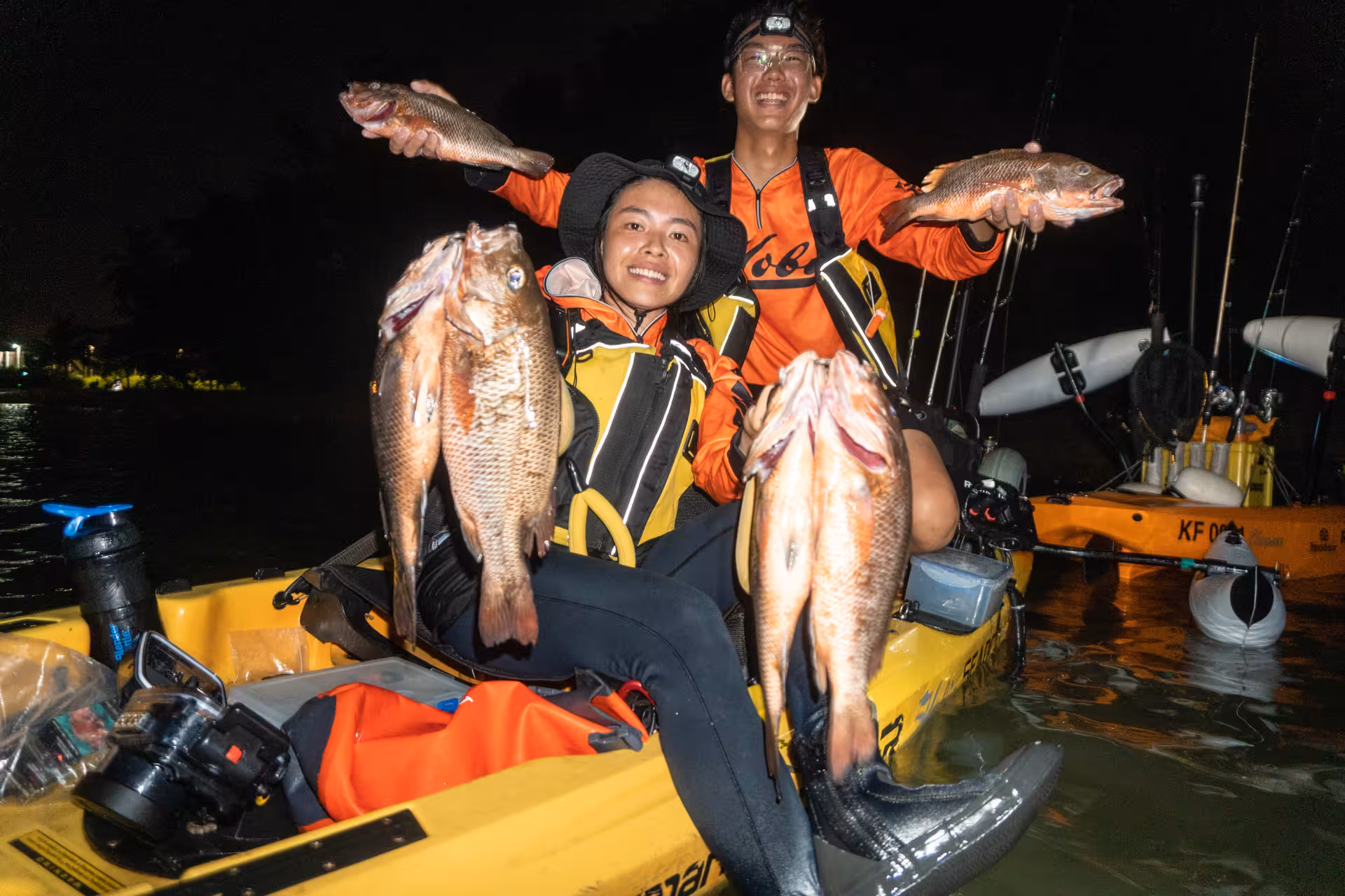 Two happy anglers show off their impressive catch during a night kayak fishing adventure at Pulau Ubin.