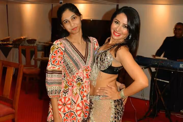 A guest poses with a belly dancer, highlighting the vibrant entertainment on a Nile cruise dinner.