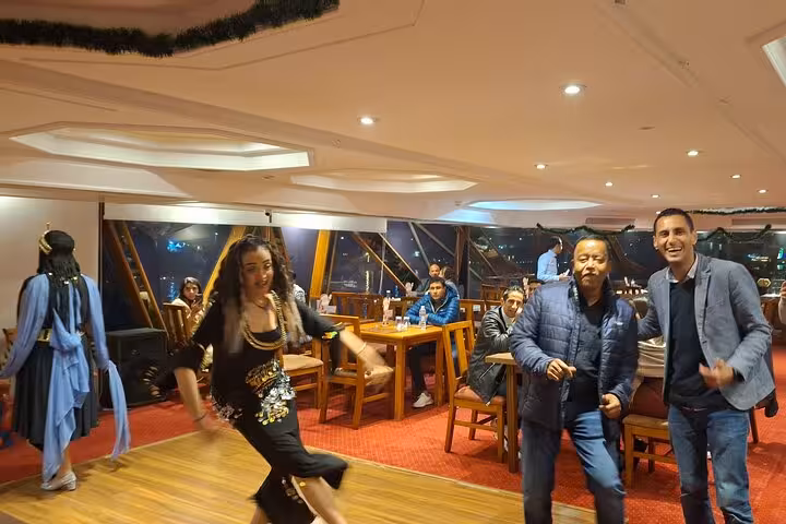 Energetic belly dancer captivating guests during a lively evening show on a Nile cruise dinner experience.