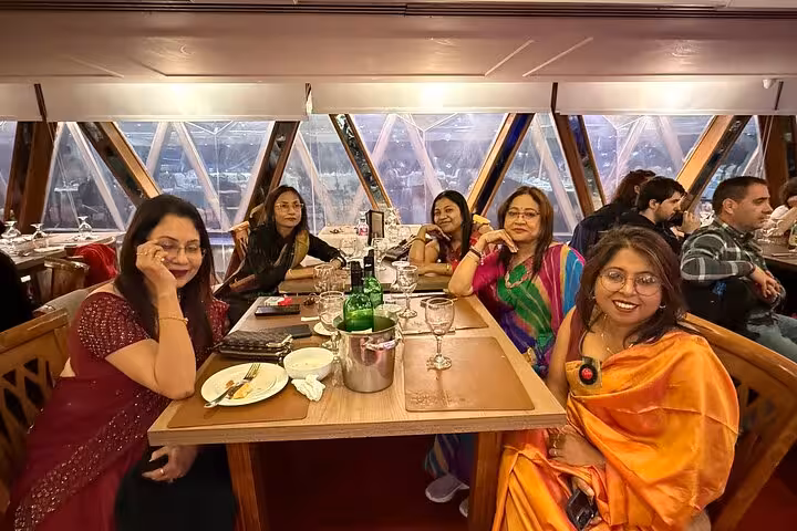 Guests seated at an elegantly set table on a Nile cruise, enjoying dinner with scenic river views.