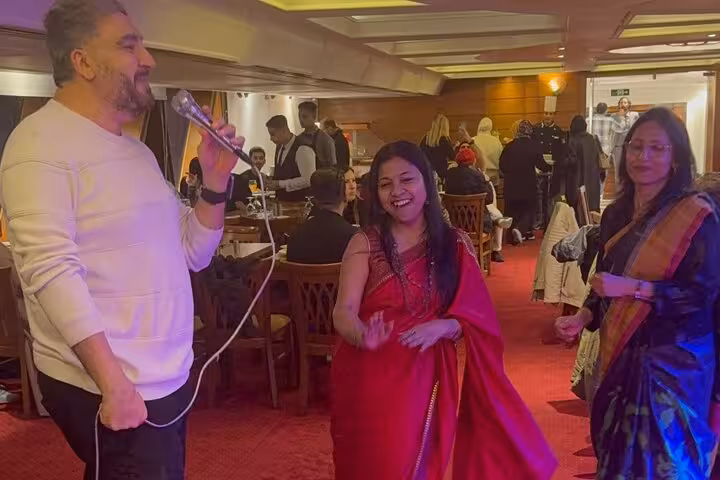 Group enjoying Nile cruise dinner with vibrant Tanura show on an elegant boat setting.