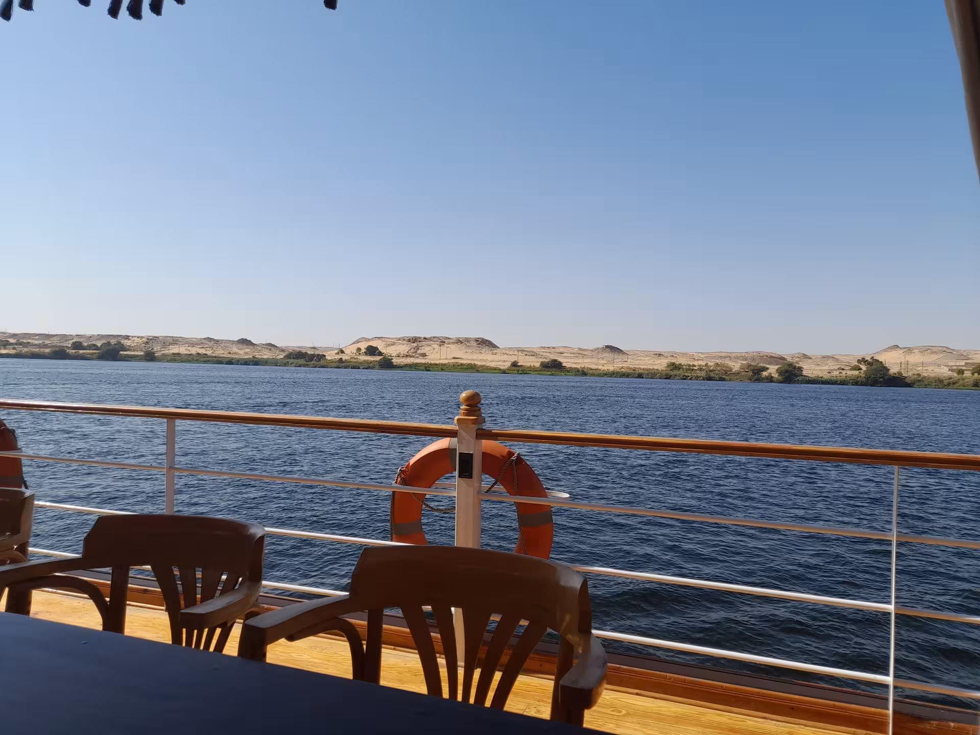 Relaxing Nile cruise view from vessel deck, showcasing serene river landscape on Luxor and Aswan Egypt multi-day trip.