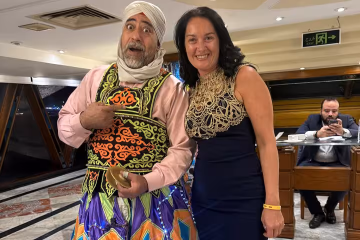 Entertainer in colorful attire with guest aboard Nile cruise featuring Tanura Show and belly dancing.