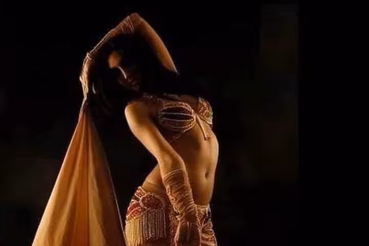 Belly dancer in sparkling costume performing onboard Nile dinner cruise night show with Oriental dance in Cairo