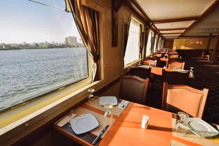 Elegant Nile dinner cruise dining room in Cairo with window views, set tables and sunset river scenery