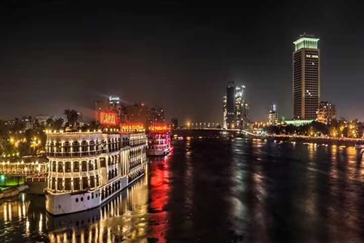 Nile dinner cruise in Cairo at night with illuminated boat and skyline reflections on the river