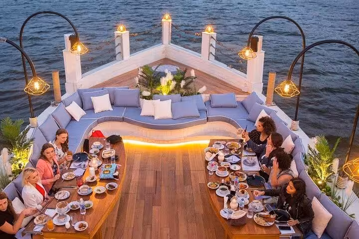 Open-air Nile dinner cruise deck with group dining under lanterns in Cairo, starlit sailing and oriental dance show