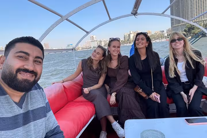 Happy travelers on a relaxing Nile felucca ride in Cairo with hotel pickup and skyline views on deck