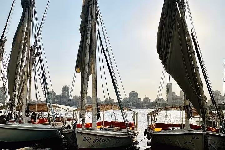 Traditional Nile felucca sailboats moored on the river with Cairo skyline, classic sailing experience in Egypt