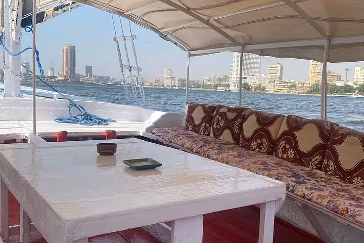 Comfortable Nile felucca seating and table with Cairo skyline views, ideal for private sailing experience on the river