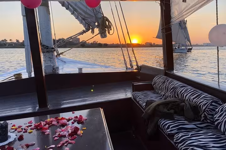 Private Nile felucca at sunset with cushioned seating and rose petals, romantic Cairo sailing cruise on the Nile