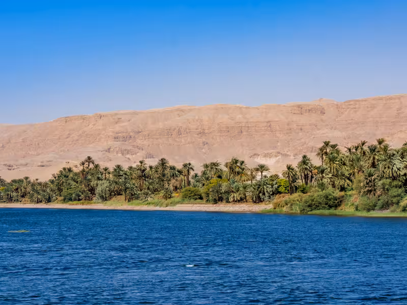 Scenic Nile River shoreline with palm oasis and desert cliffs, viewed on a 5-star Nile Jewel cruise in Egypt