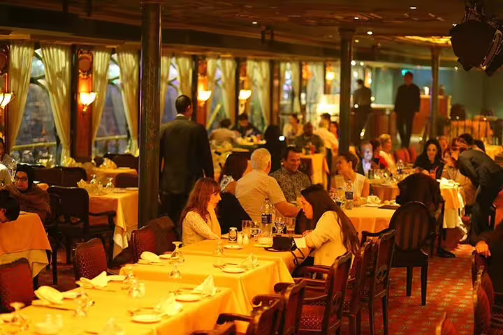 Wide view of Nile Maxim dinner cruise dining hall in Cairo with set tables and evening Oriental show atmosphere