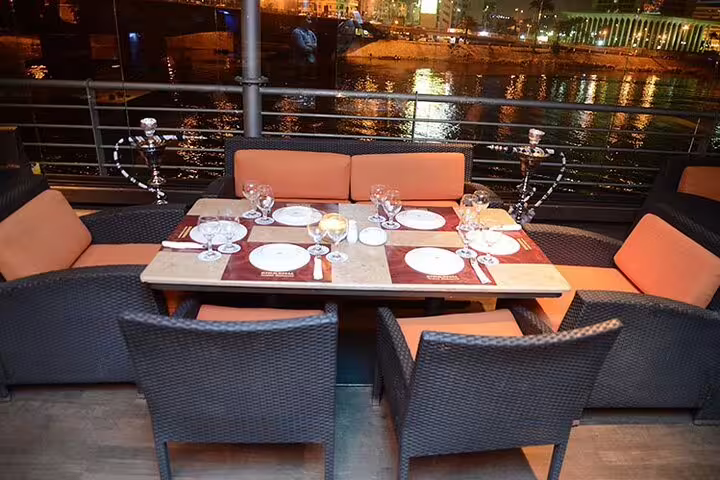 Outdoor dining table set on Nile Maxim dinner cruise Cairo at night, river views and dinner show atmosphere