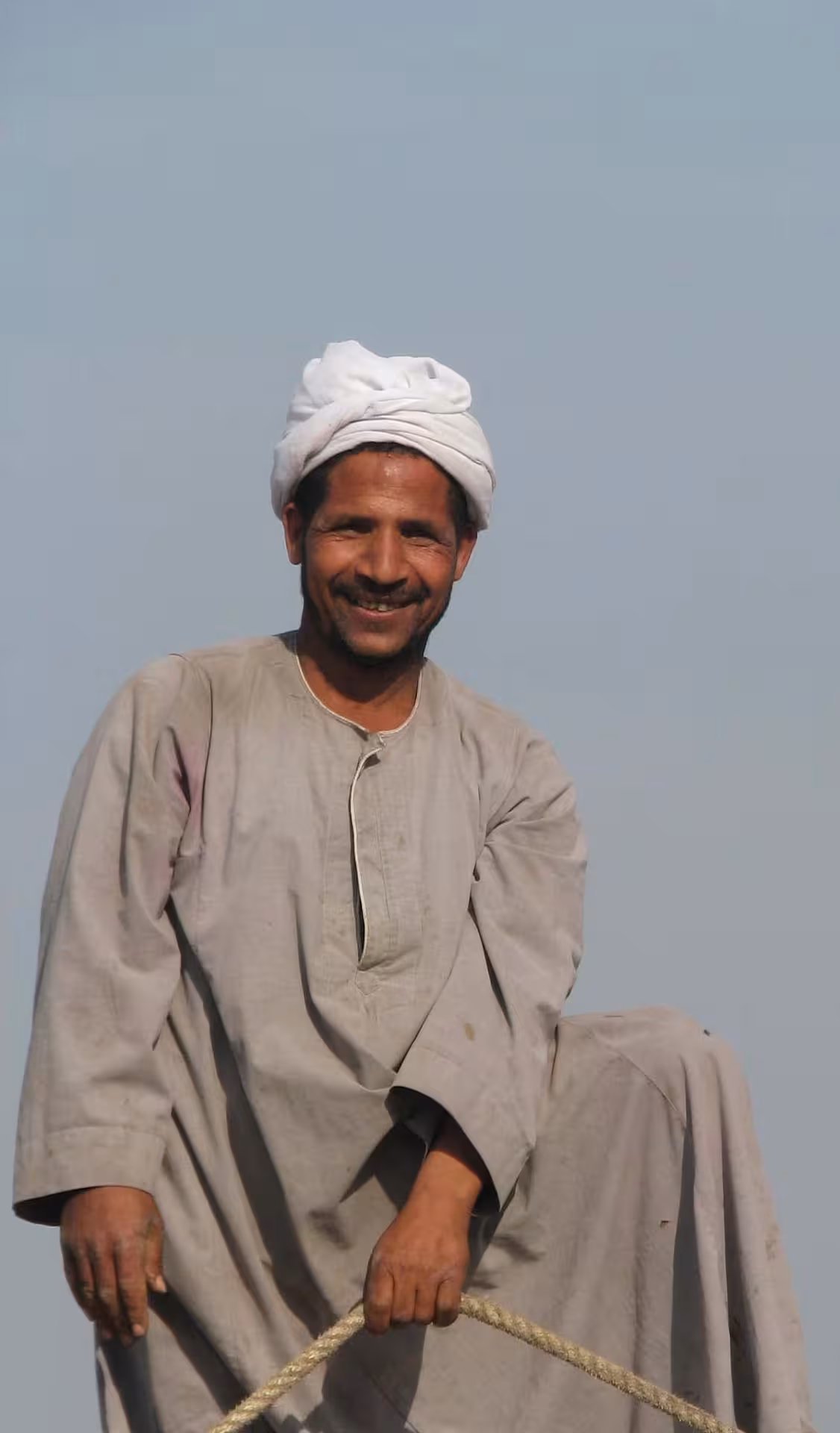 Smiling Egyptian crew member on Nile Pearl 5-star Nile Cruise, traditional galabeya and turban on deck