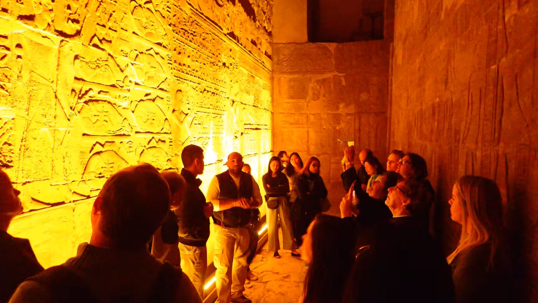 Guided group explores illuminated temple hieroglyphs on Nile Pearl 5-star Nile cruise shore excursion in Egypt