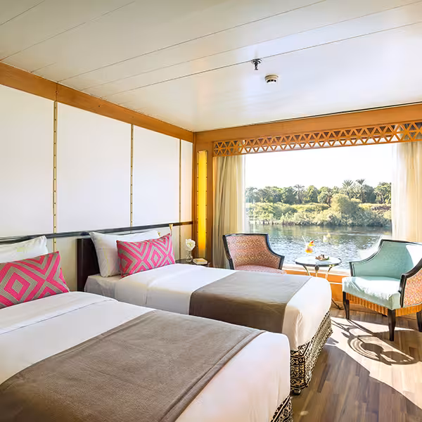 Twin cabin on Nile Pearl 5-star Nile Cruise with river-view window, modern decor and relaxing seating