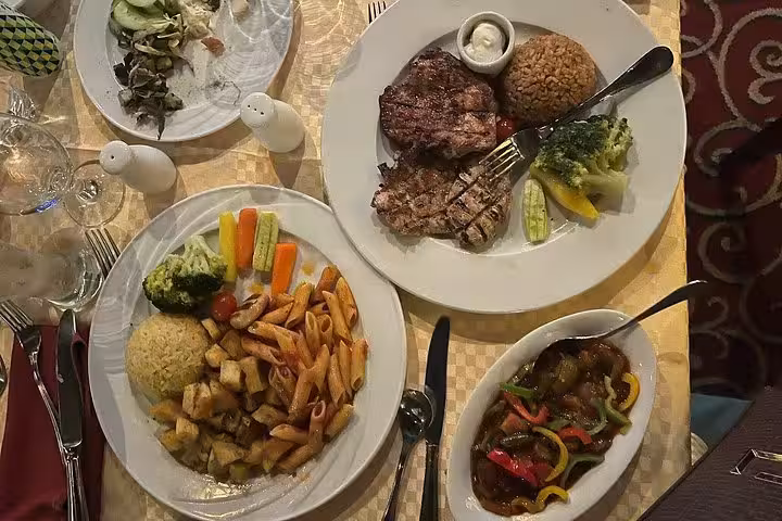 Assorted dinner plates with grilled meat, pasta, vegetables and salad served on a Nile River dinner cruise
