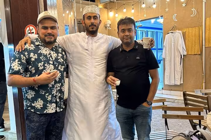 Guests share traditional Omani coffee with a local host in Nizwa, enjoying evening culture on a Nizwa by Night sightseeing tour