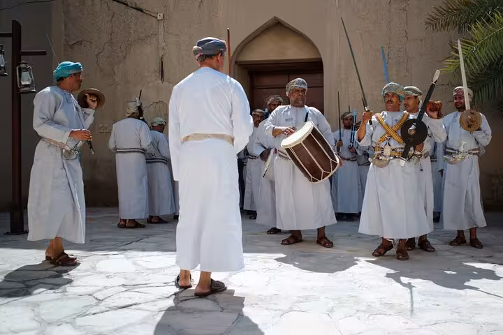 Omani musicians and dancers in traditional dress performing inside Nizwa Fort during a private evening cultural tour