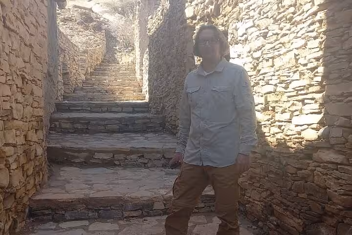 Traveler exploring ancient stone alley and steps of a traditional mountain village on a full-day Nizwa group tour in Oman