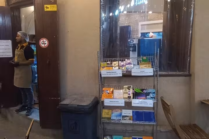 Bookstall with Islamic literature outside a cozy café in Nizwa souq, a cultural stop on the Private Evening Trip to Nizwa
