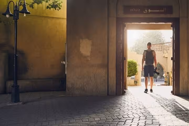 Traveler with backpack enters Nizwa souq at sunset, starting a guided Nizwa by Night sightseeing tour through old town markets