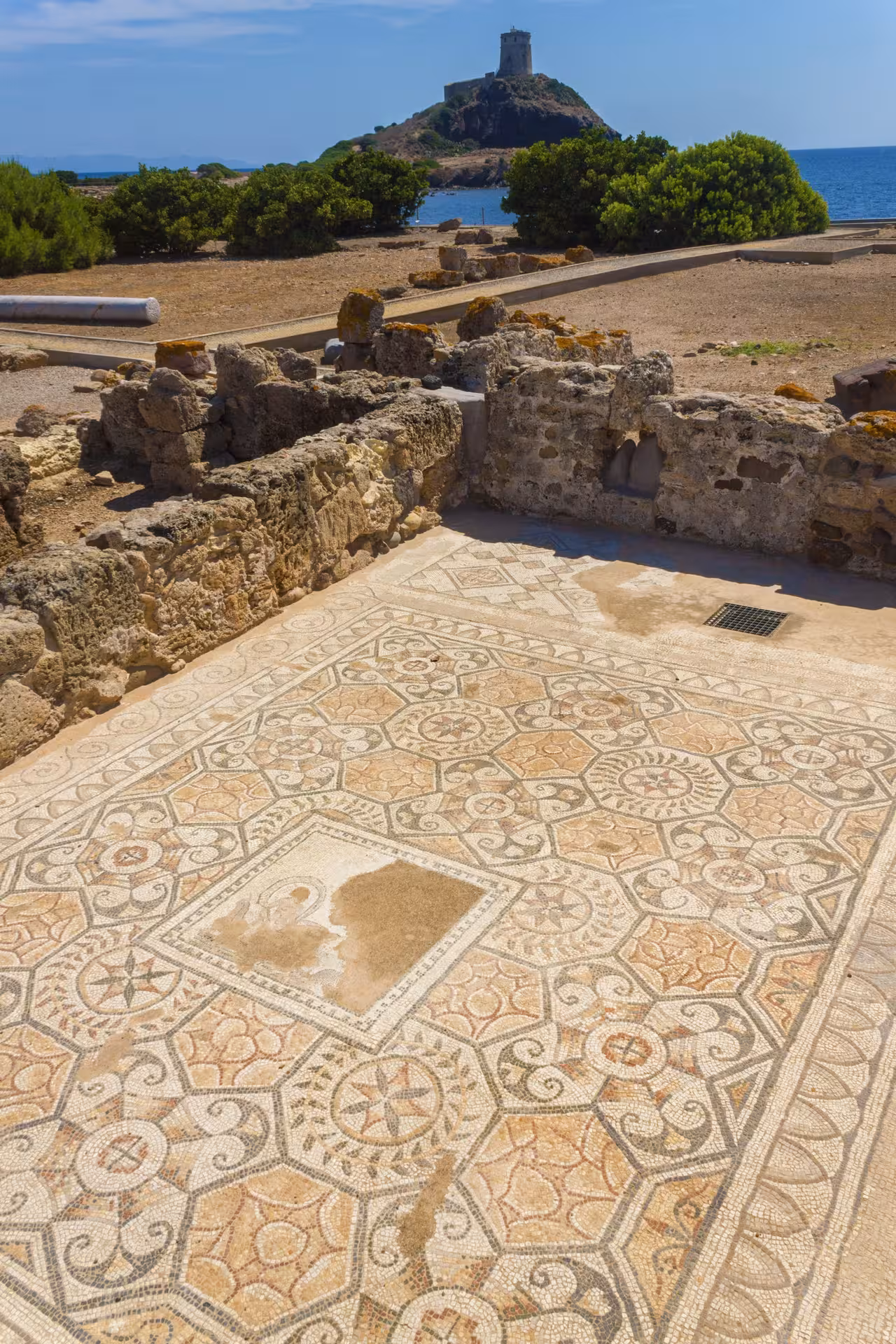 Admire intricate mosaic floors and ancient ruins at the archaeological site of Nora with a scenic coastal backdrop.
