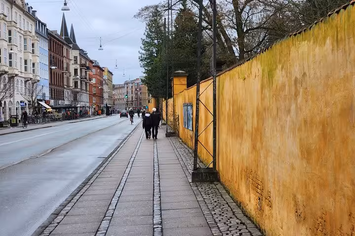 Vibrant yellow wall and cobblestone path in Copenhagen, showcasing local architecture for an immersive walking tour.