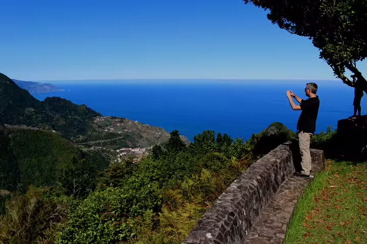 Tourist captures stunning ocean and mountain views on a full day guided tour of Northeast Madeira's breathtaking landscapes.