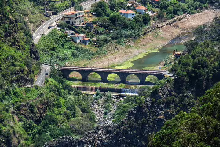 Scenic view of an arched stone bridge and lush greenery in Northeast Madeira, highlighting the island's natural beauty on a guided tour.