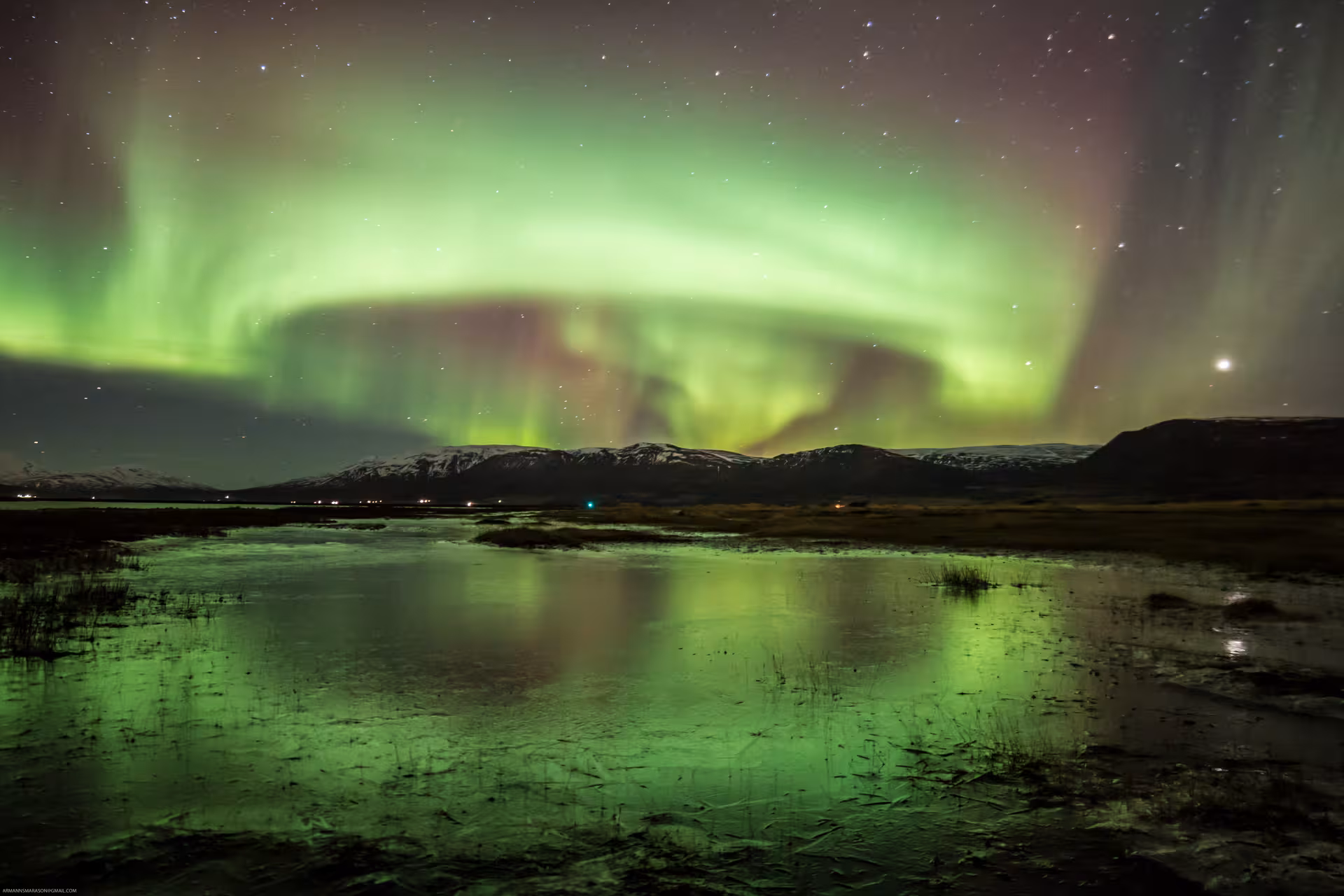 Vibrant Northern Lights illuminate the night sky over Icelandic mountains on the Akureyri tour.