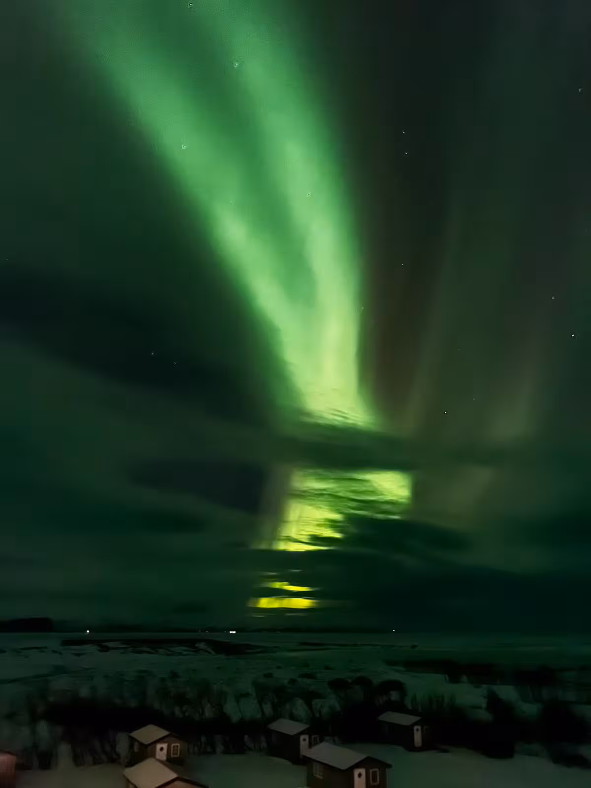 Northern Lights illuminate the Icelandic sky over a snowy landscape during a women's New Year's Eve adventure tour.