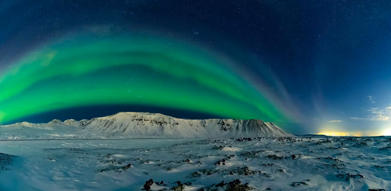 Breathtaking Northern Lights over snowy Icelandic landscape, highlighting Reykjavík's natural beauty.
