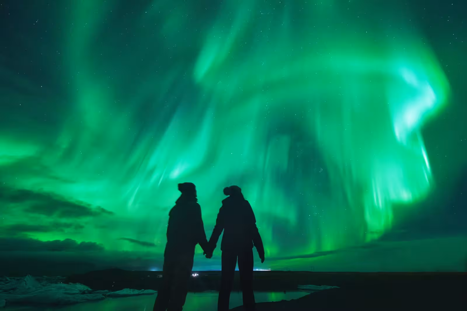Couple marveling at the Northern Lights during a Reykjavík stopover, ideal for aurora seekers.