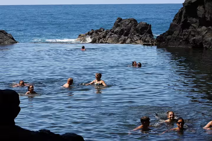 People enjoying swimming in natural volcanic pools with ocean views during a 4x4 tour of the Northwest Terraces.