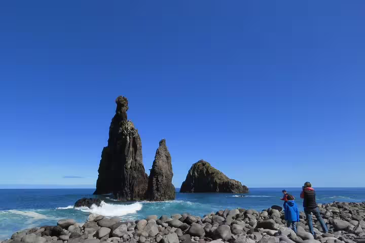 Group enjoying sunny day by volcanic pools with clear blue waters on Northwest Terraces 4x4 shore excursion.