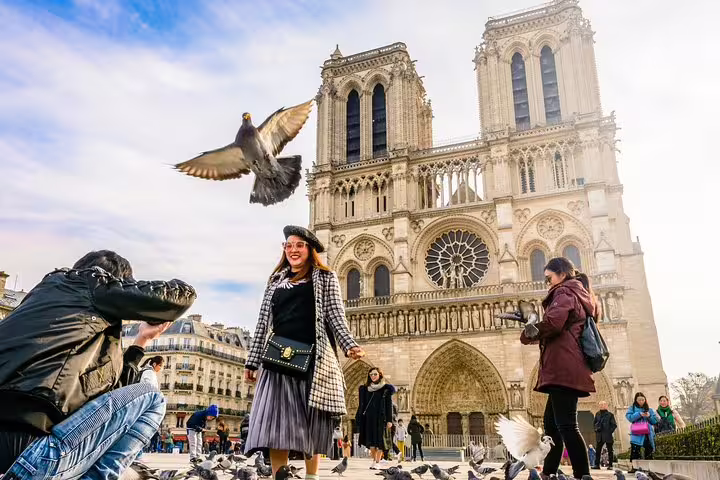 Tourists enjoy the lively atmosphere and stunning architecture outside the iconic Notre-Dame Cathedral in Paris, surrounded by pigeons.